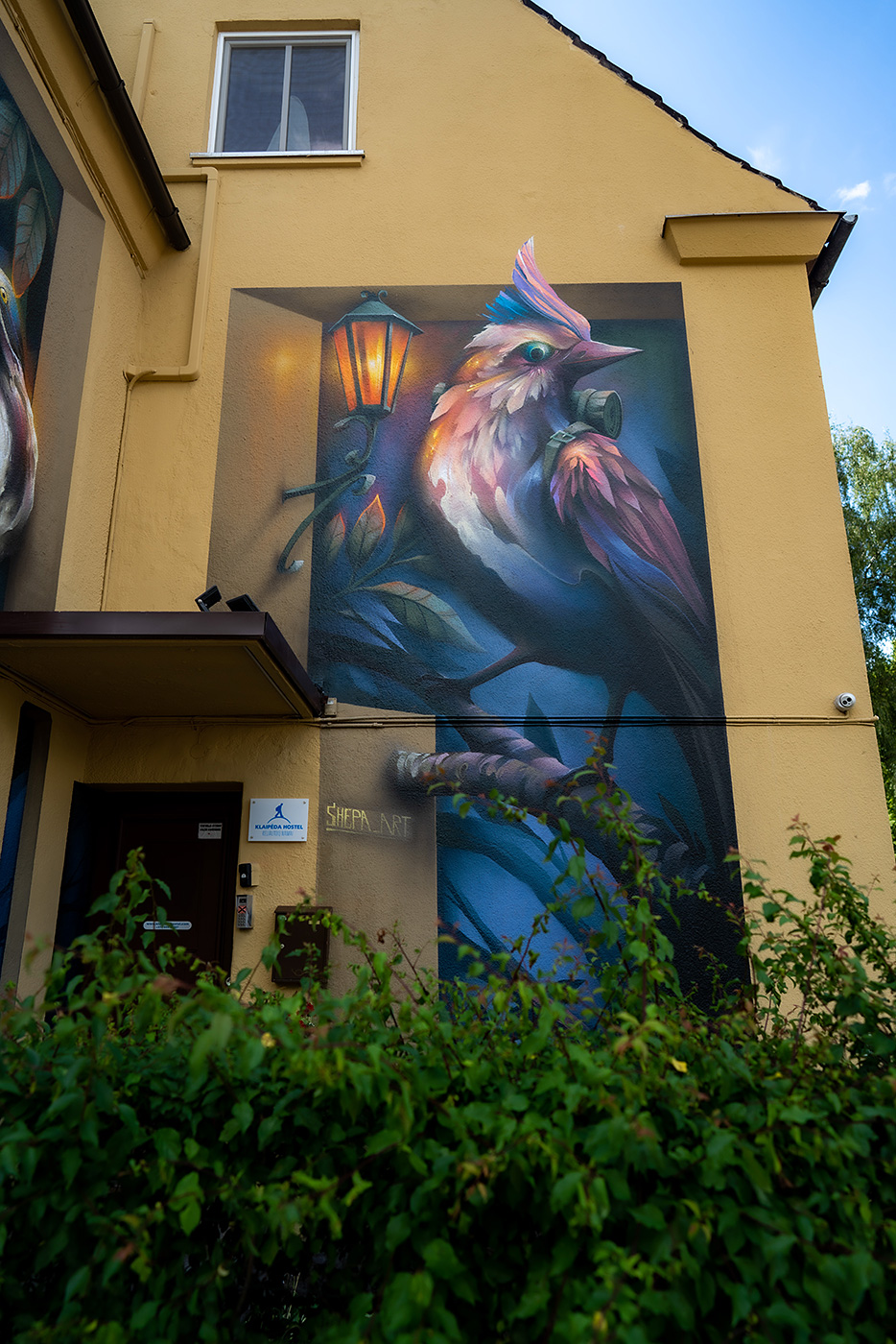 A mural of a three-dimensional bird painted next to the entrance of the Klaipeda Hostel