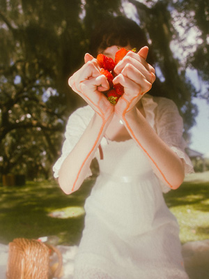 Model squeezing strawberries as the red juice drips down her arms. Her arms hide her face