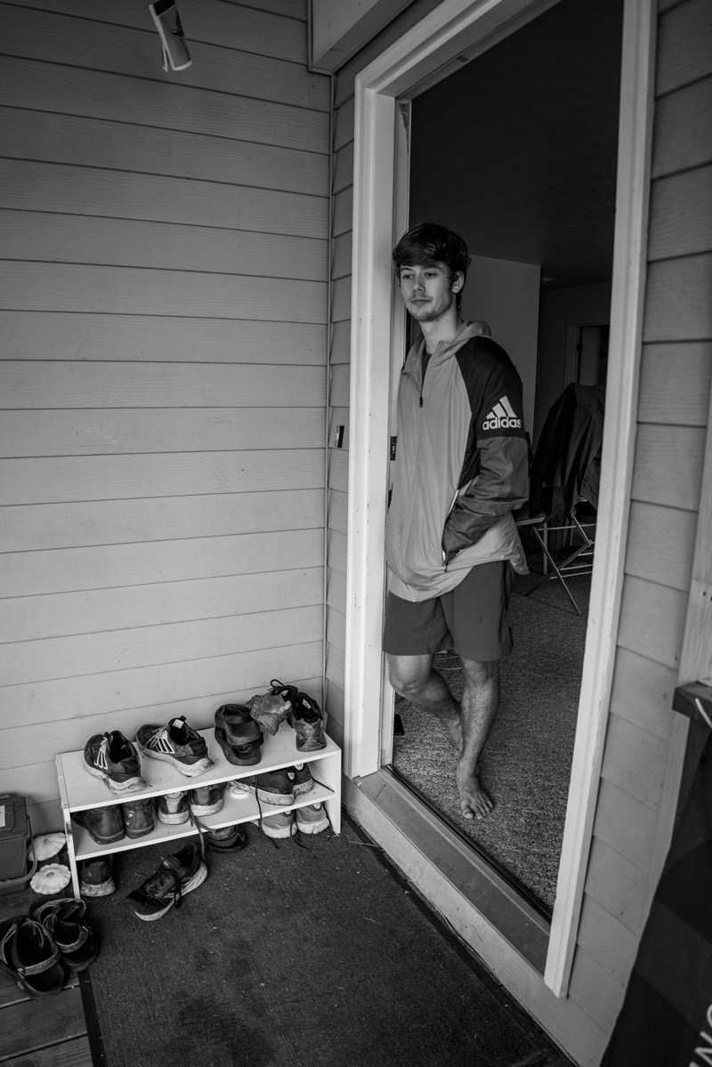 Jonas stands in the doorway to his apartment talking to people outside.