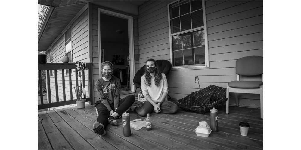 Roommates Andrea (left) and Laura (right) sit laughing together with their finished lunches beside them.