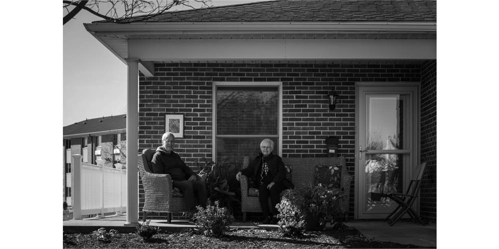 Duane (left) and Lois (right) sit together talking on the front porch of their new home.