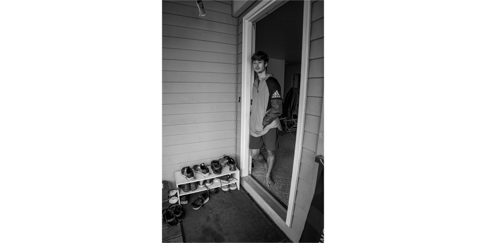 Jonas stands in the doorway to his apartment talking to people outside.