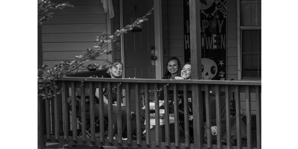 Janessa, Anna, ad Kate (left to right) eat lunch together on their porch which they wound with lights and decorated for the Halloween season.