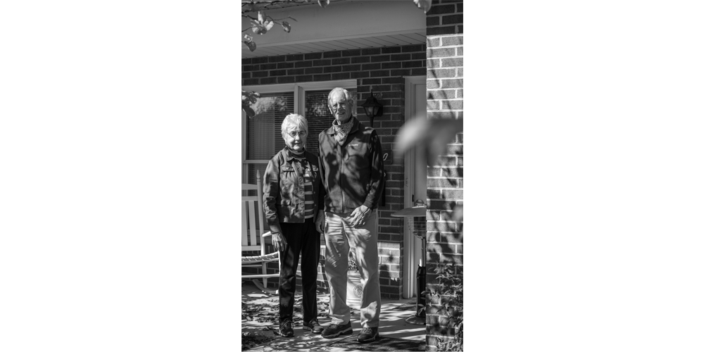 Darlene (left) and Roland (right) stand on the front porch of their home enjoying the sunshine together.