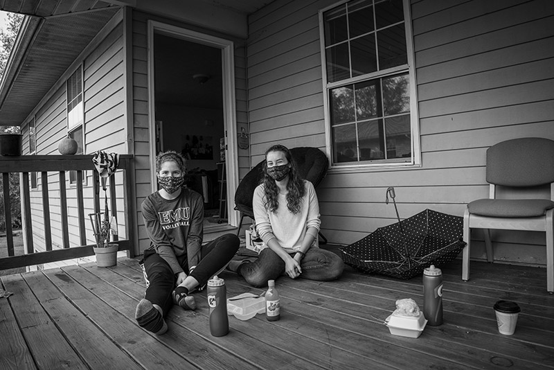 Roommates Andrea (left) and Laura (right) sit laughing together with their finished lunches beside them.