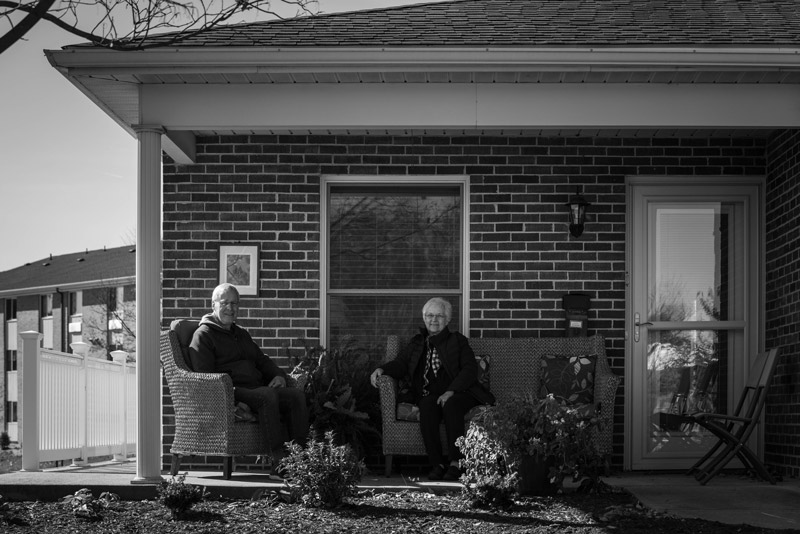 Duane (left) and Lois (right) sit together talking on the front porch of their new home.