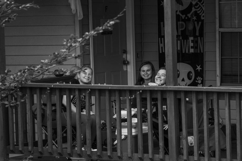 Janessa, Anna, ad Kate (left to right) eat lunch together on their porch which they wound with lights and decorated for the Halloween season.