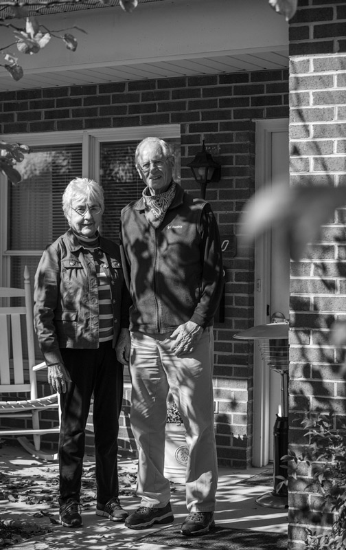 Darlene (left) and Roland (right) stand on the front porch of their home enjoying the sunshine together.